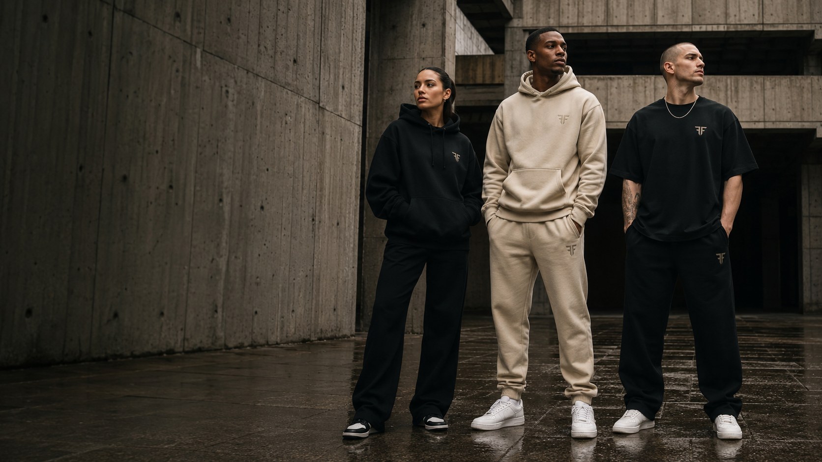 Three models in black and sand Faith Above Fear hoodies and tracksuits standing on a wet concrete plaza